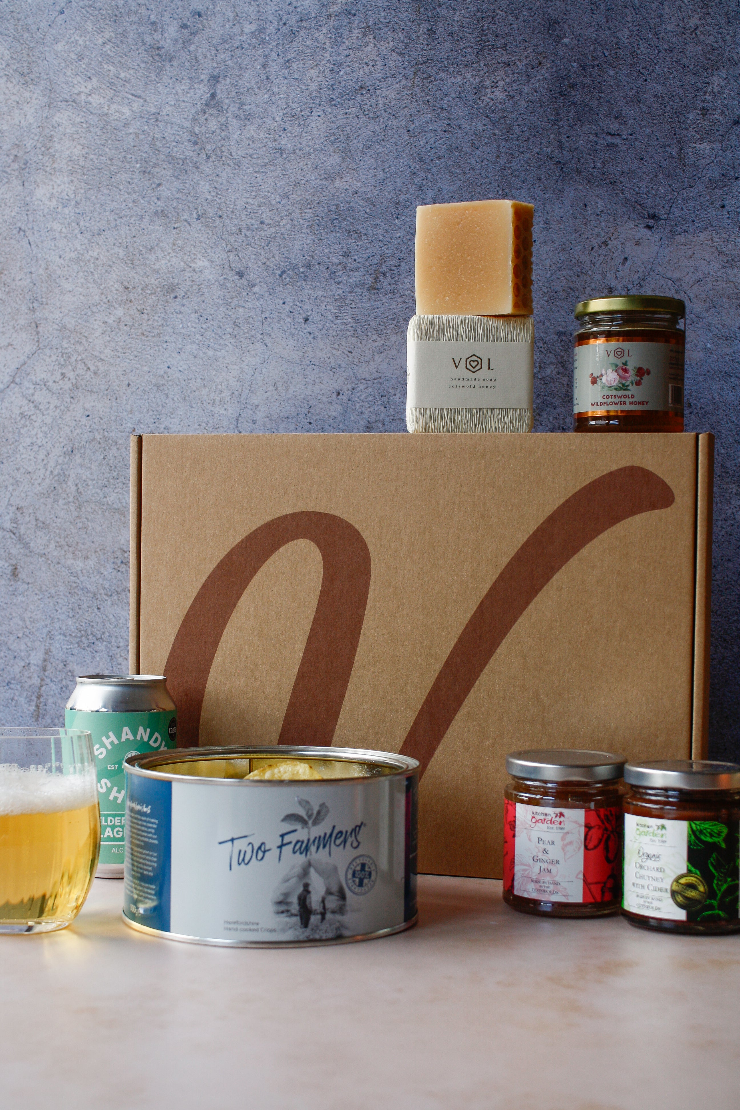 Assorted food products with crisps, a can of drink, assorted jars and soap on a textured background