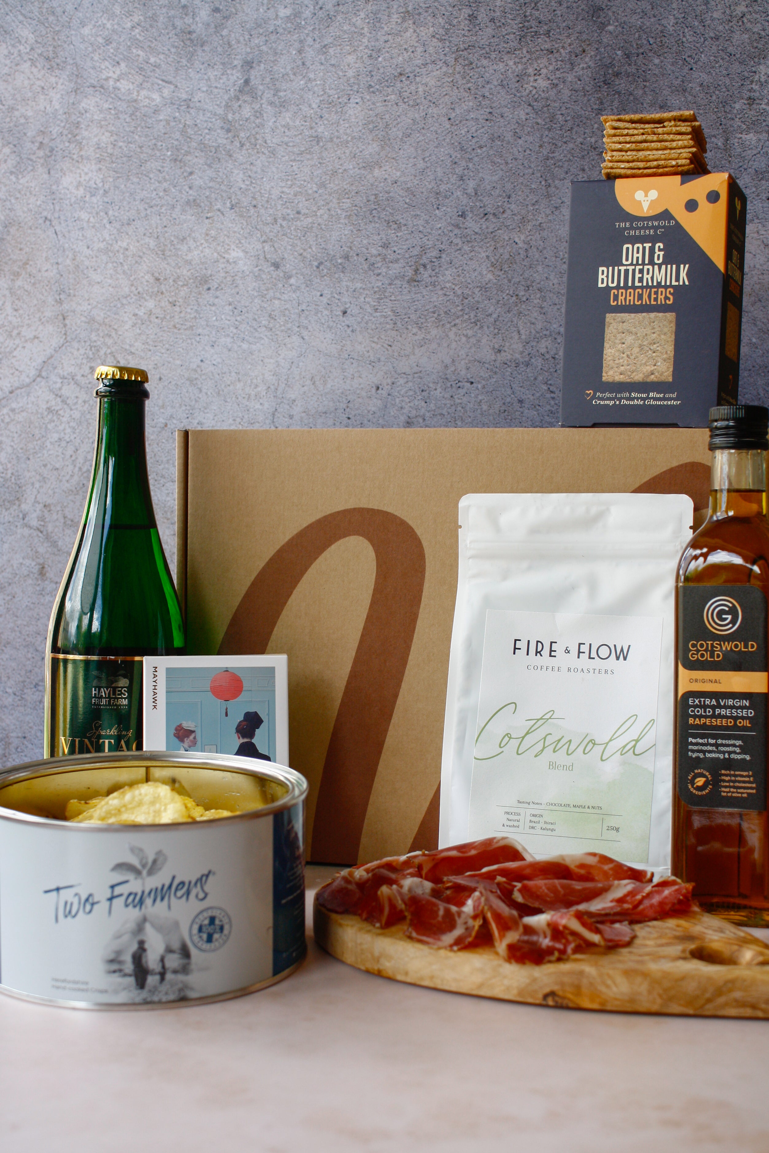 Assorted food items including a bottle, cheese, crackers, and a box on a gray background