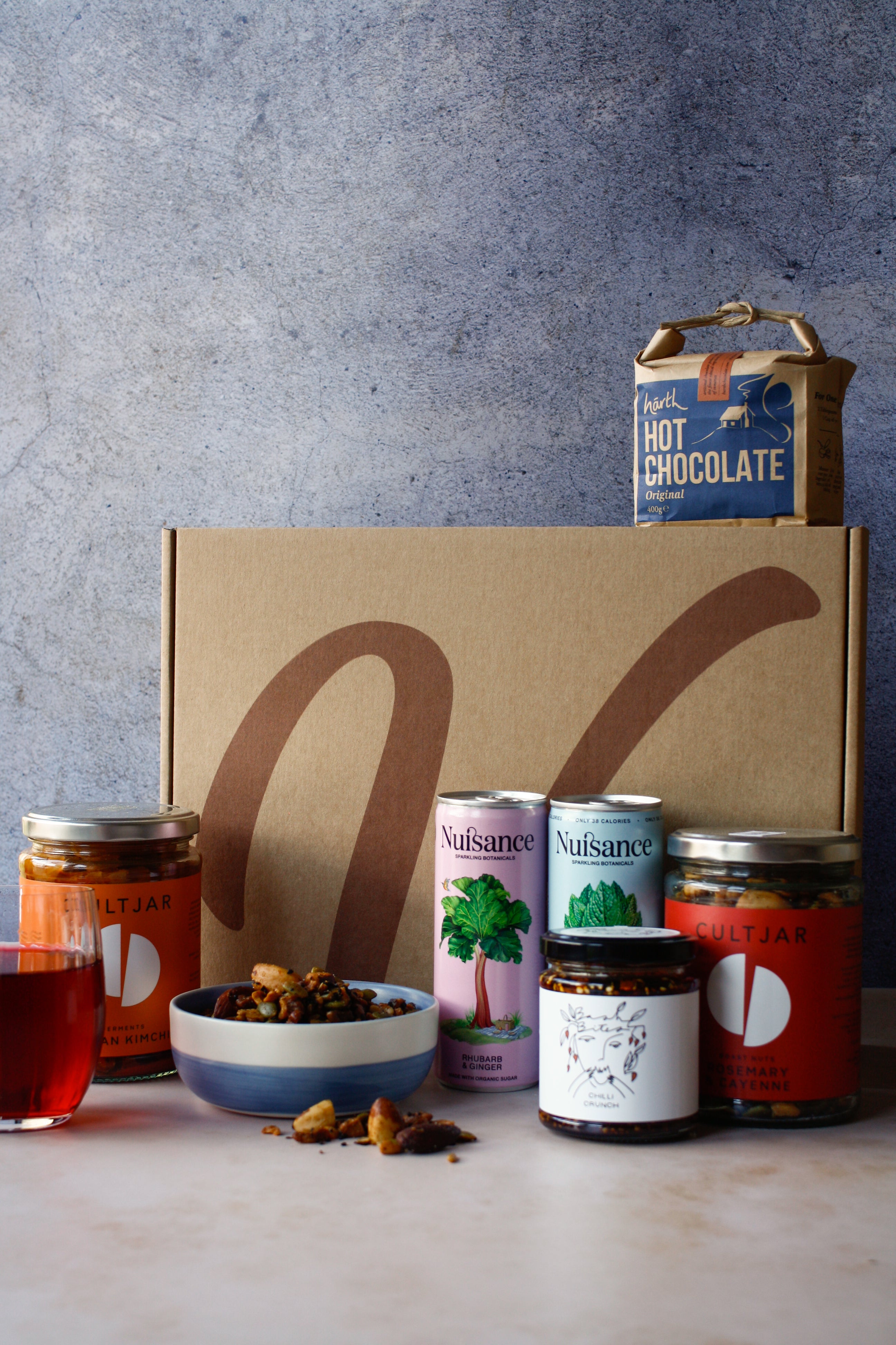 Collection of vegan food products including hot chocolate, cans of drink, nuts and assortment of jars