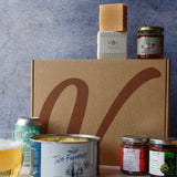 Assorted food products with crisps, a can of drink, assorted jars and soap on a textured background