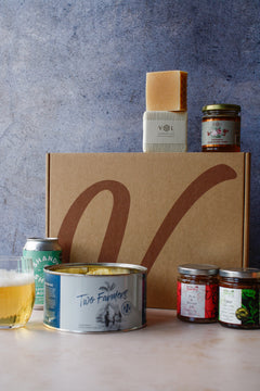 Assorted food products with crisps, a can of drink, assorted jars and soap on a textured background