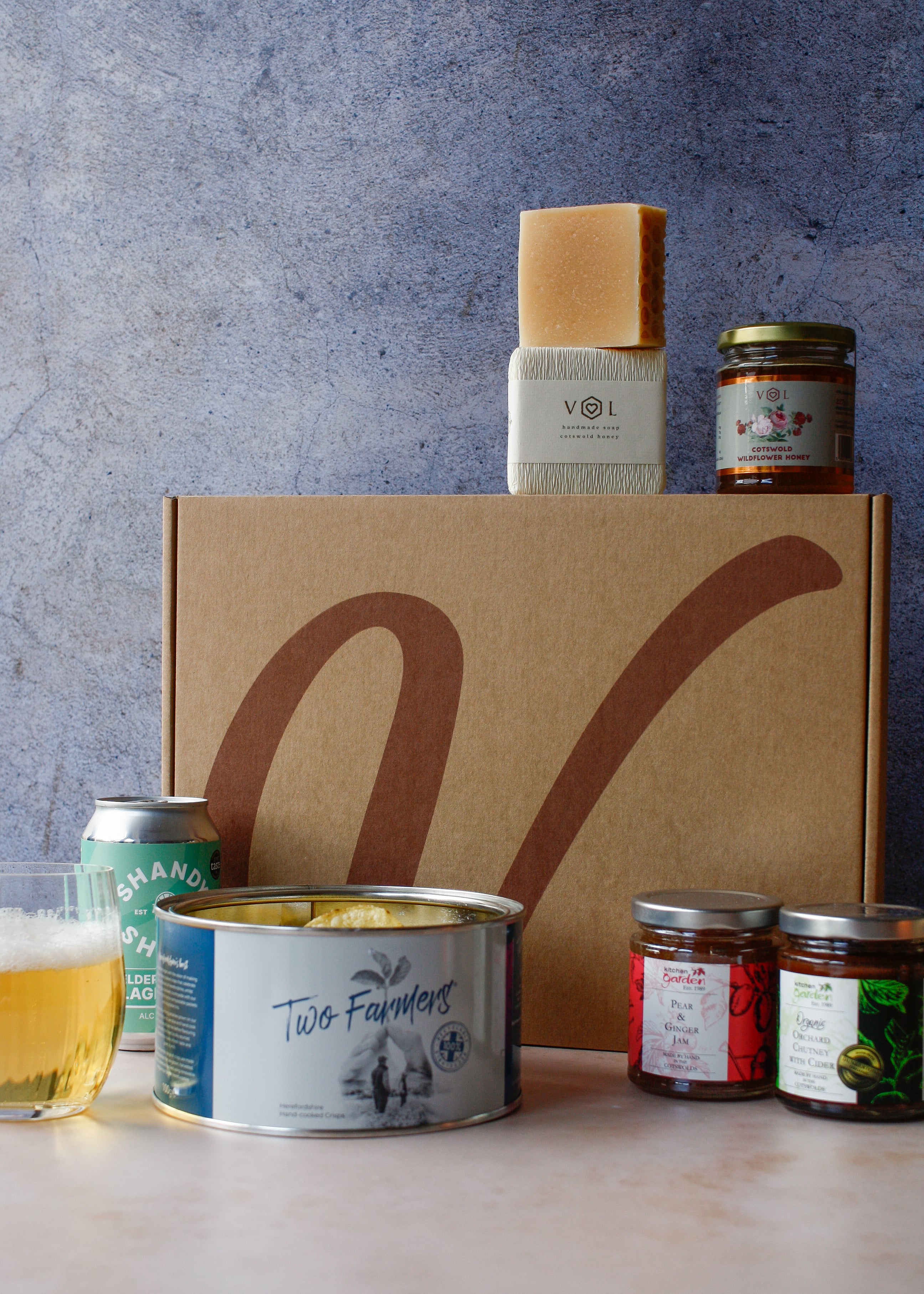 Assorted food products with crisps, a can of drink, assorted jars and soap on a textured background