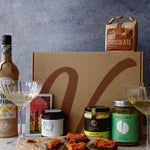 Gourmet gift set with hot chocolate, wine bottle, chocolate and assortment of jars with a textured background