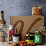 Gourmet gift set with hot chocolate, wine bottle, chocolate and assortment of jars with a textured background