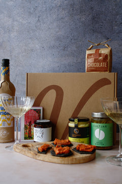 Gourmet gift set with hot chocolate, wine bottle, chocolate and assortment of jars with a textured background