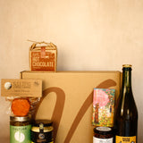 Collection of gourmet items including a bottle, jars, and a box on a beige background