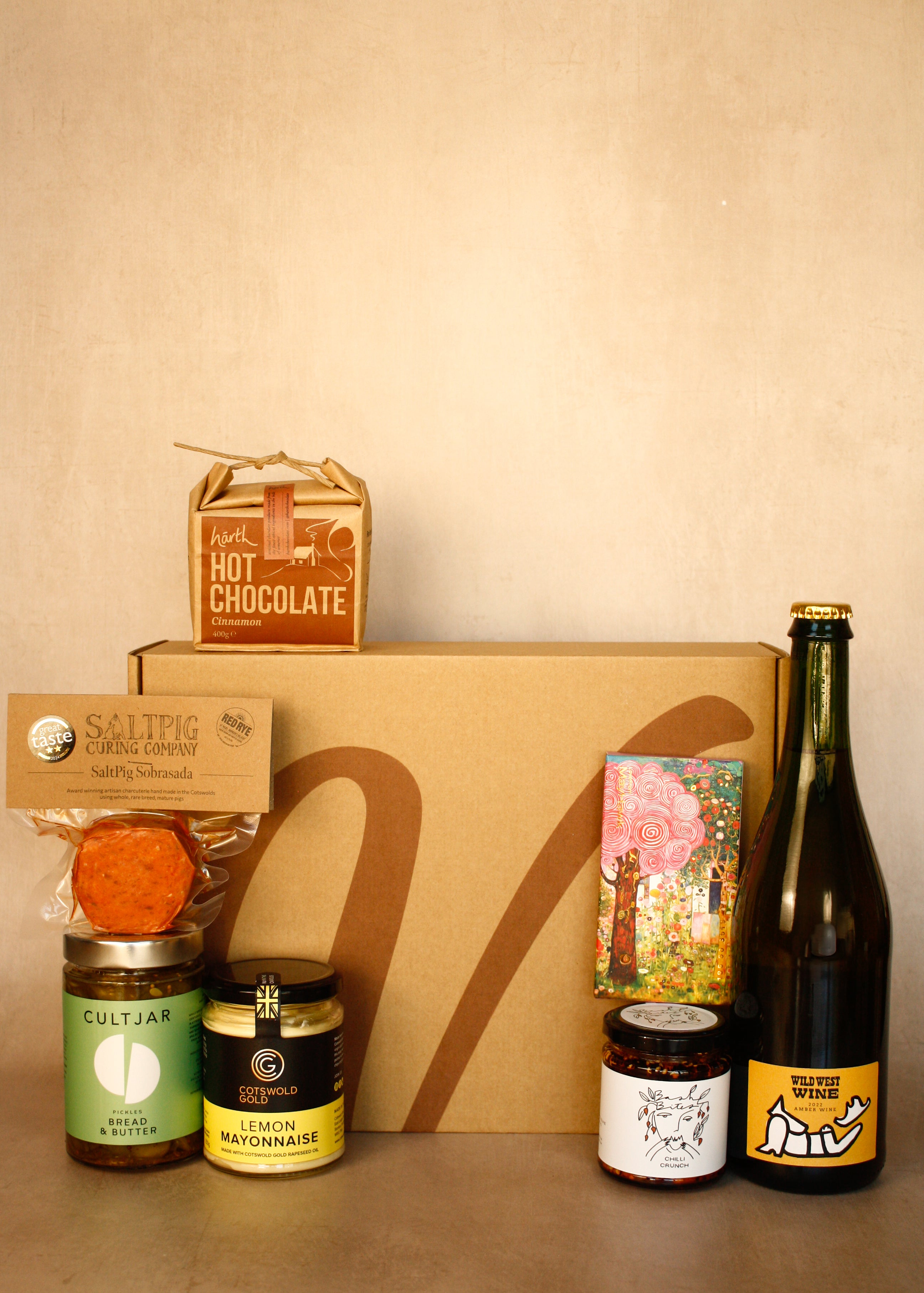 Collection of gourmet items including a bottle, jars, and a box on a beige background