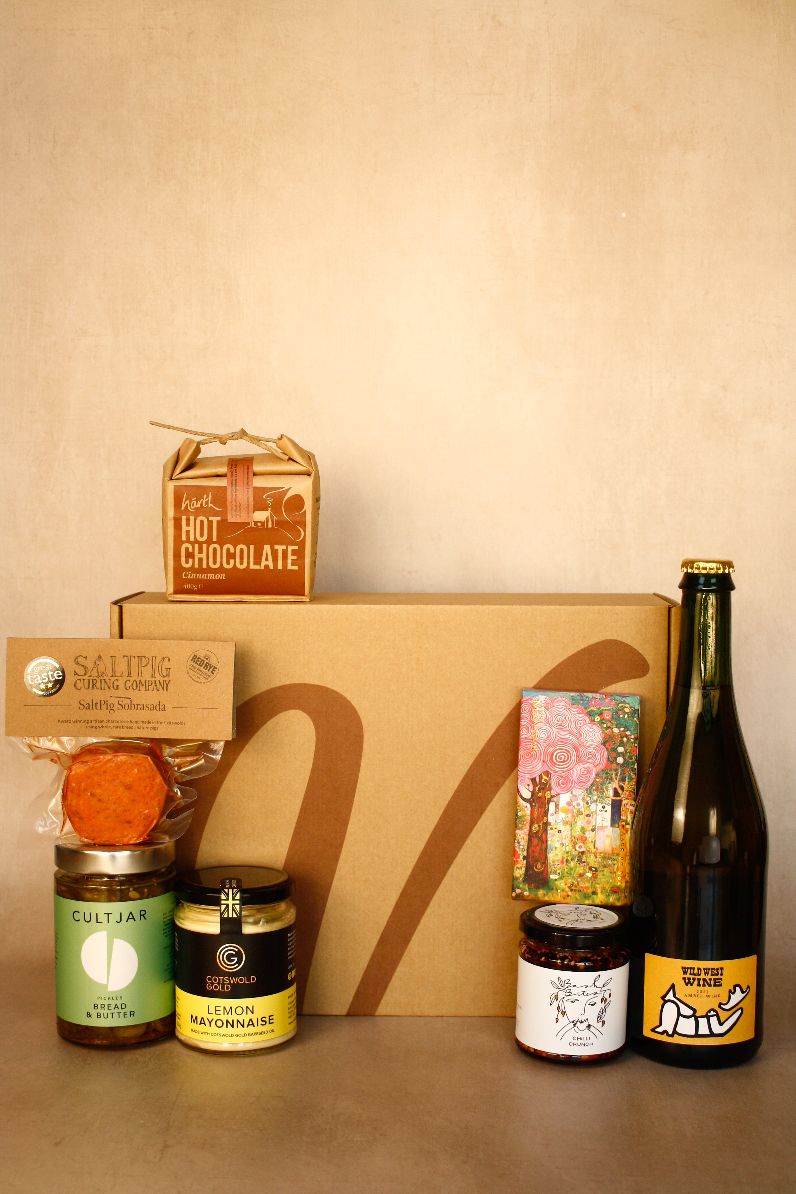 Collection of gourmet items including a bottle, jars, and a box on a beige background
