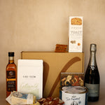 Gourmet food and wine gift set with a bottle of wine, cheese, and crackers on a wooden board.