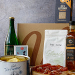 Assorted food items including a bottle, cheese, crackers, and a box on a gray background