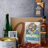 Assorted food items including a bottle, a can, a box, and a jar on a table with a gray background.