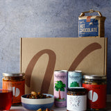 Collection of vegan food products including hot chocolate, cans of drink, nuts and assortment of jars