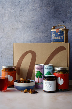 Collection of vegan food products including hot chocolate, cans of drink, nuts and assortment of jars