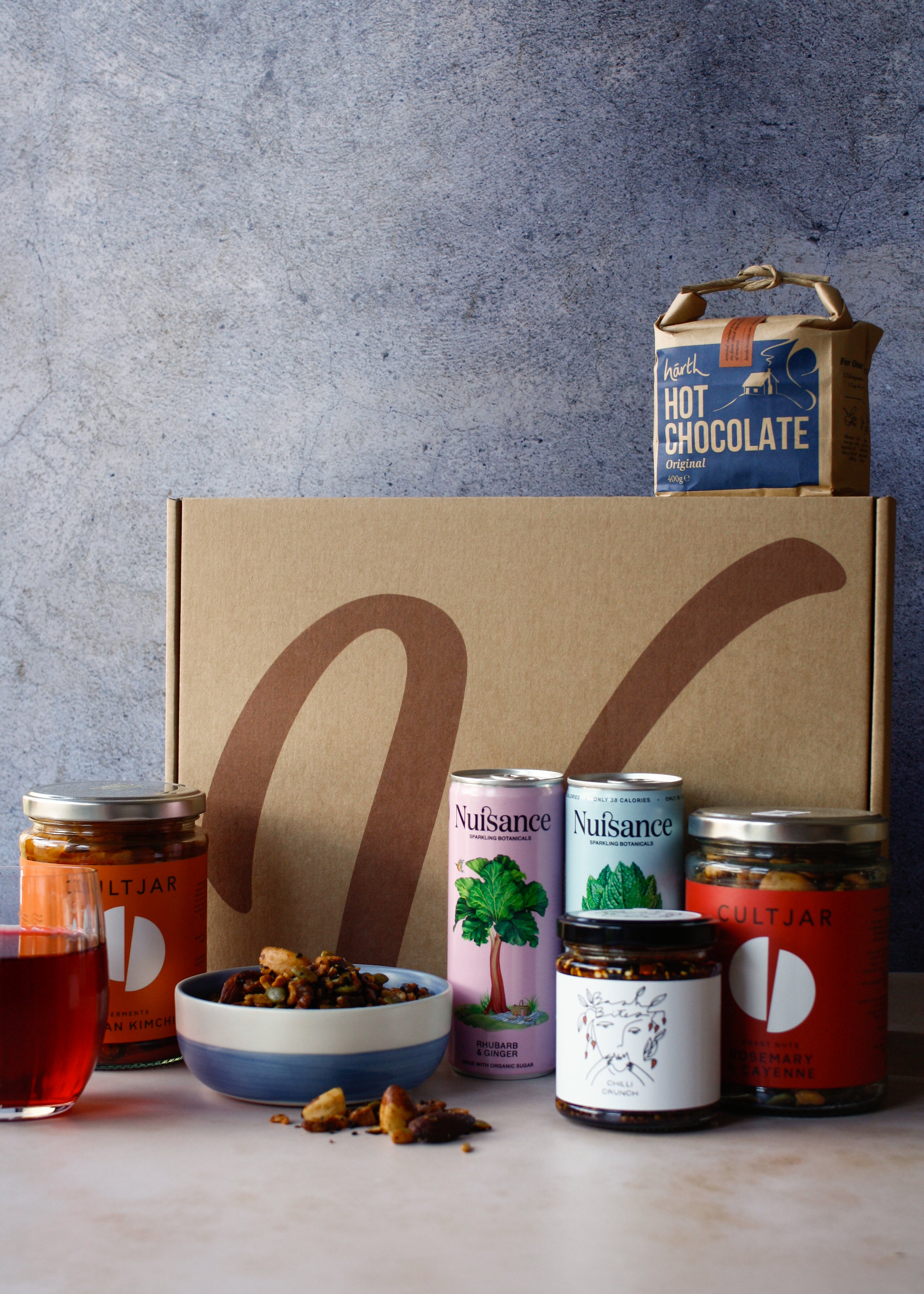 Collection of vegan food products including hot chocolate, cans of drink, nuts and assortment of jars