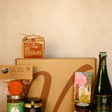 Collection of gourmet items including hot chocolate, cider, and various jars on a beige surface.