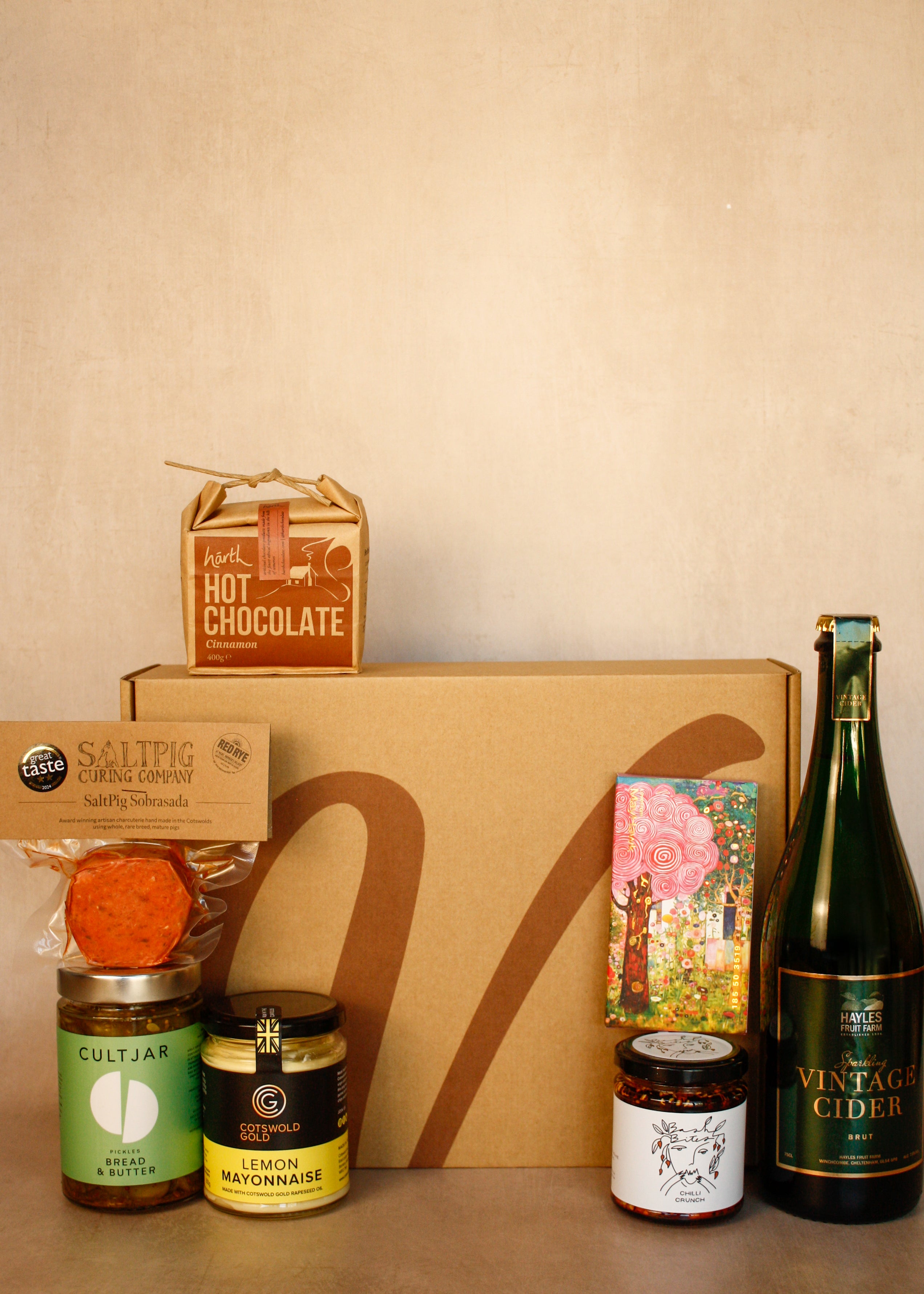 Collection of gourmet items including hot chocolate, cider, and various jars on a beige surface.